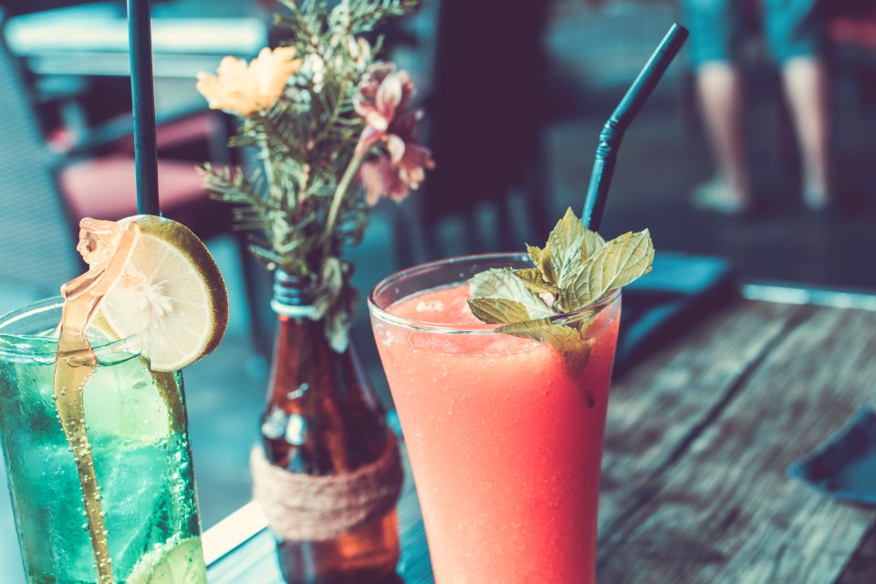 Glass Of Fruit Juice Next To A Bottle With Flowers And Clear Glass Cup