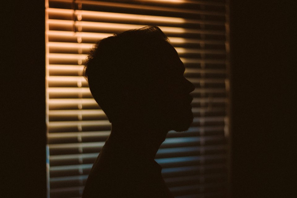 Mans Silhouette Near White Window Blinds
