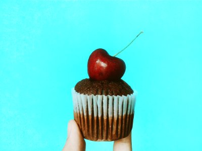 Person Holding Chocolate Cupcake With Cherry Topping