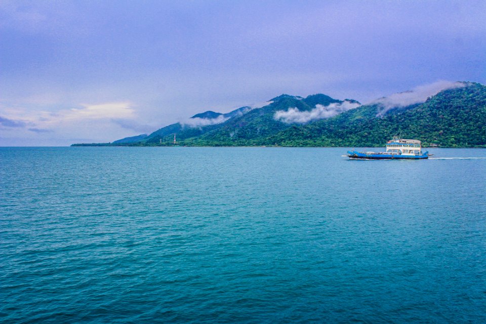 Blue And White Yacht On Teal Sea Near Green Mountain