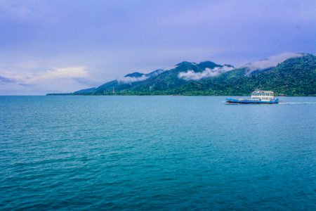 Blue And White Yacht On Teal Sea Near Green Mountain