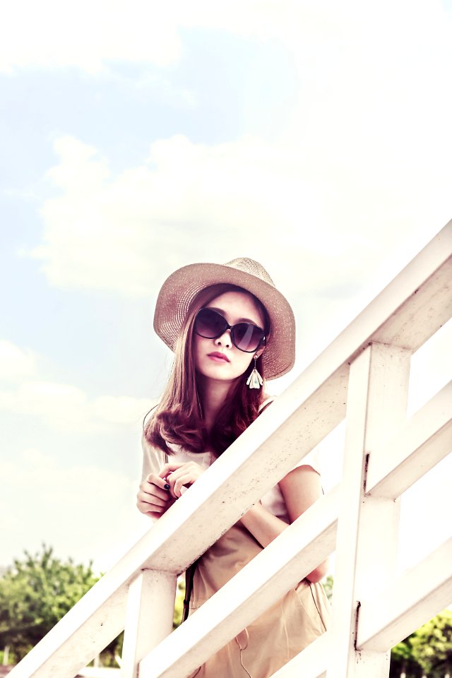 Woman Wearing Gray Sun Hat In Front Of White Fence