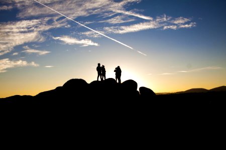 Silhouette Photo Of People On Top Of Rock Formation photo