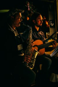 Two Men Playing Saxophone And Acoustic Guitar During Night Time