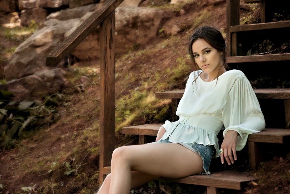 Woman Wearing White Long Sleeve Shirt Sitting On Brown Wooden Stairs