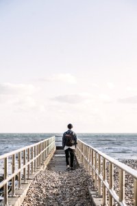 Man In Black Jacket Walking On Gray Concrete Dock