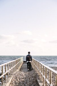 Man In Black Jacket Walking On Gray Concrete Dock photo