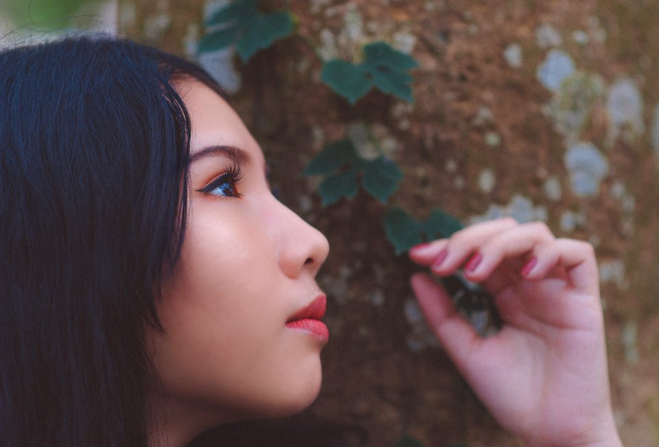 Close Up Photo Of Woman Looking Up Near Tree Trunk