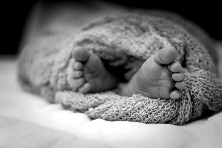 Greyscale Photo Of Human Feet Covered In Knitted Comforter photo