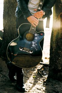 Man Holding Single Cutaway Acoustic Guitar photo