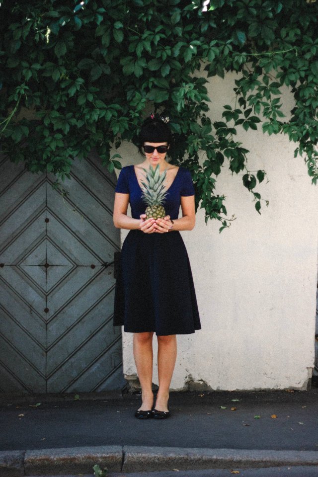 Woman Holding Pineapple Standing Beside Wall photo