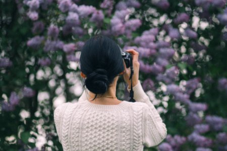 Woman Holding Camera Taking Photos Of Flowers photo