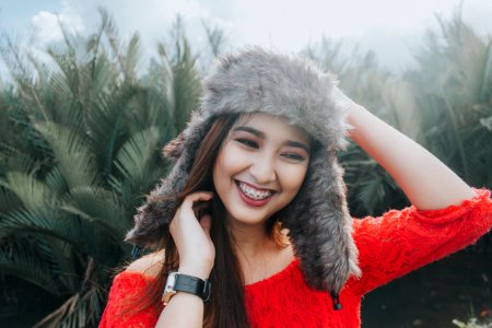 Woman In Red Off Shoulder Top Wearing Fur Beanie Smiling For Photo photo