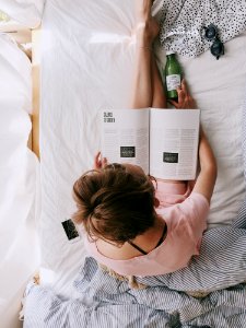 Woman In Pink Dress Sitting On Bed While Reading photo