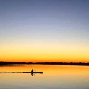 Silhouette Of Man Inside Of Boat Sailing On Body Of Water During Sunset photo
