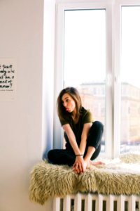 Woman In Green Shirt And Black Denim Jeans Sitting Near Window Inside Room