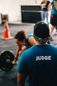Man In Blue Crew-neck Shirt Staring At Woman Trying To Lift Barbell photo