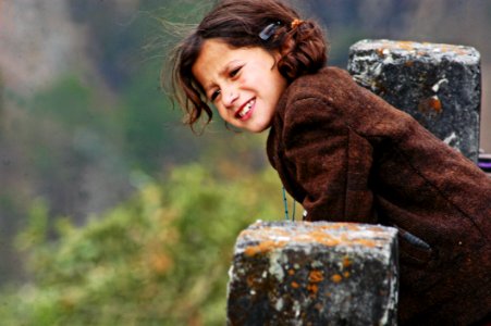 Girl Wearing Brown Coat Leaning On Concrete Pillar photo