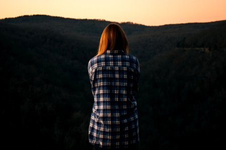 Woman Wearing Blue And White Plaid Dress Shirt In Front Of Green Mountain