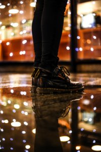 Photo Of Person Wearing Black Fitted Jeans And Black Drmartens Boots Standing On Black Floor Tiles photo