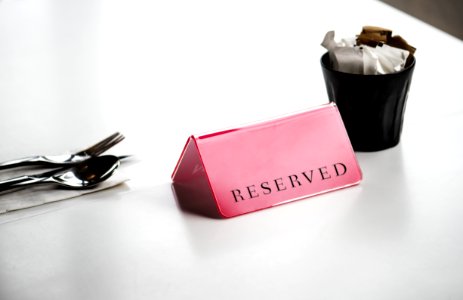 Red Reserved Signage Beside Stainless Steel Spoon And Fork On White Surface photo