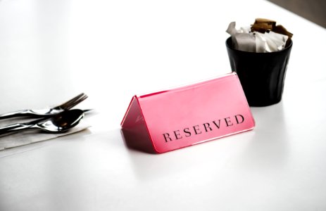 Red Reserved Signage Beside Stainless Steel Spoon And Fork On White Surface