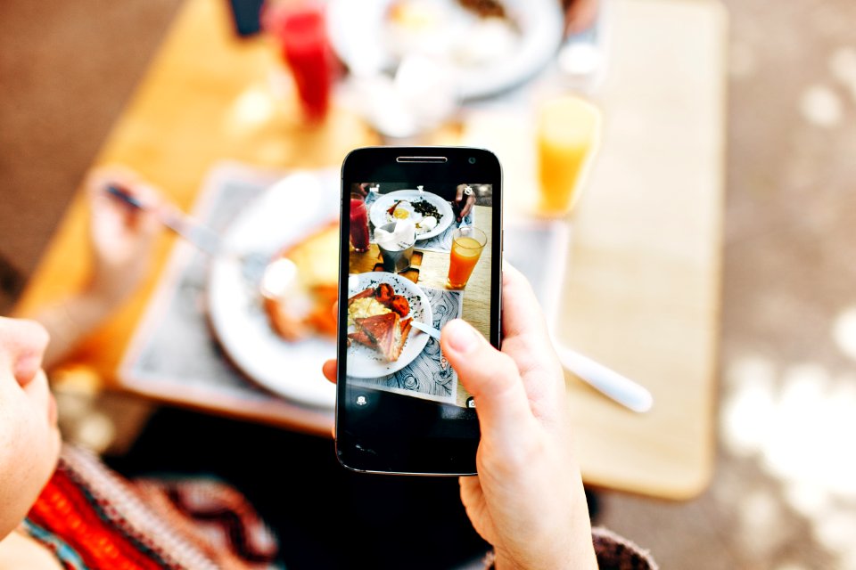 Person Holding Phone Taking Picture Of Served Food