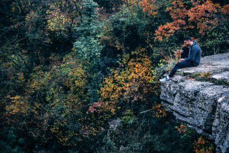 Man In Hoodie Sitting On Rock Cliff photo