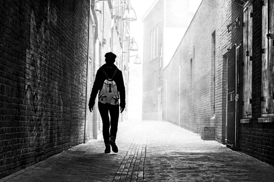 Grayscale Photo Of Person Near Brick Wall photo