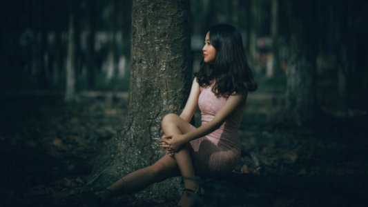 Selective Focus Photography Of Woman Wearing Pink Dress Sitting On Tree Roots photo