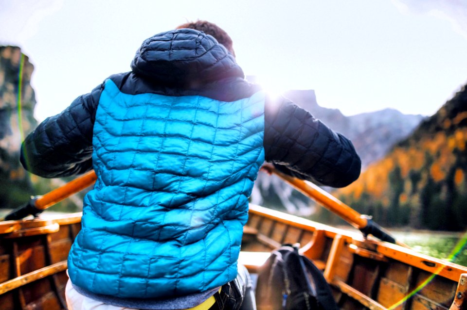 Man In Blue Vest Holding Paddle Sitting Inside Boat photo