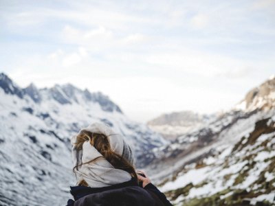 Person Wearing Black Jacket In Front Of Mountain Filled With Snow