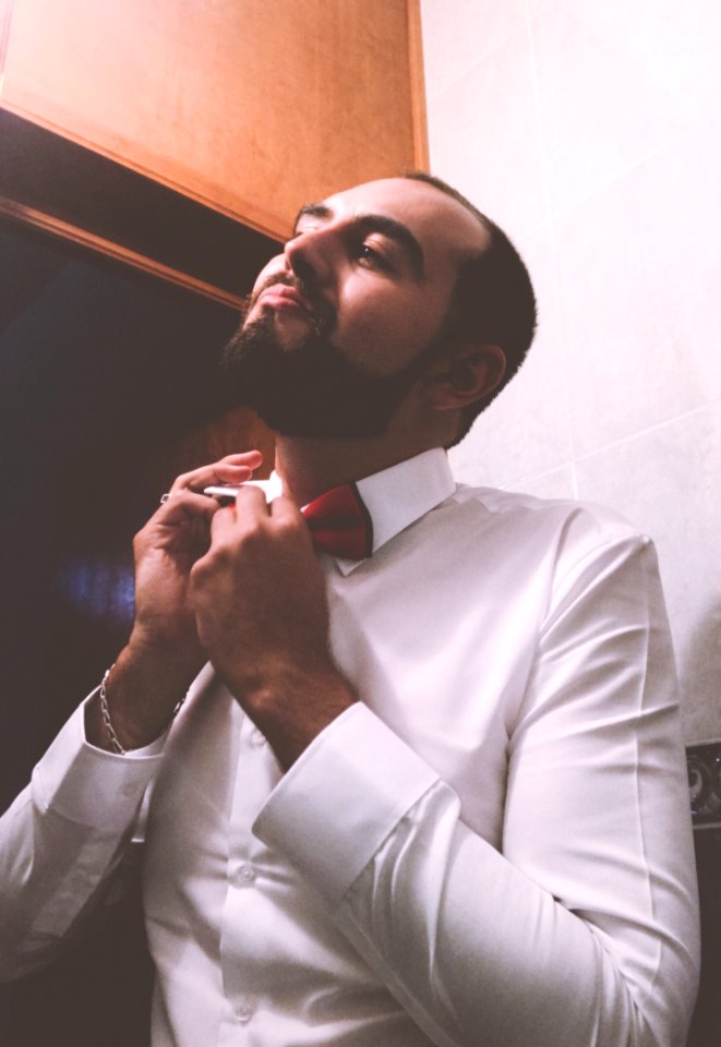 Man In White Dress Shirt Tying A Red Bow Tie