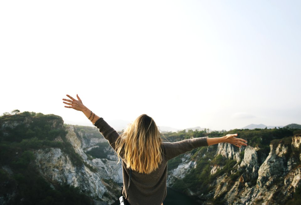 Woman With Blonde Hair At The Top Of The Mountain Raising Her Hands