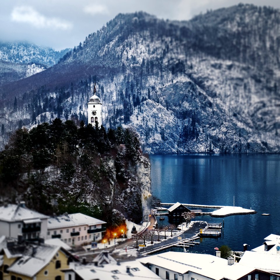 Snow Covered Mountain Houses Near Body Of Water At Daytime