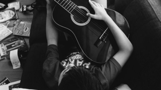 Man Playing Guitar Lying On Couch In Grayscale Photography photo