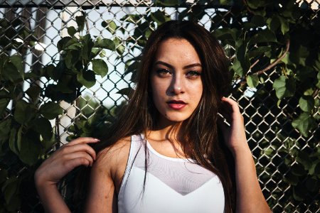 Woman In White Tank Top Standing Near Gray Metal Wire Fence photo