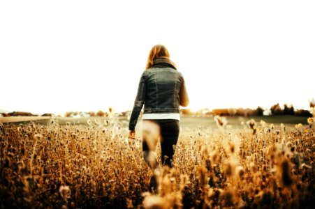 Woman In Blue Denim Jacket Walking On Field photo