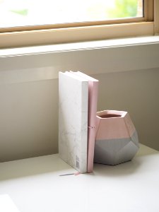 White And Pink Books Piled Beside Pink And Gray Ceramic Vase photo