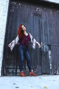 Woman In Red Tank Top With Brown Scarf Standing Near Black Wooden Door Closed photo