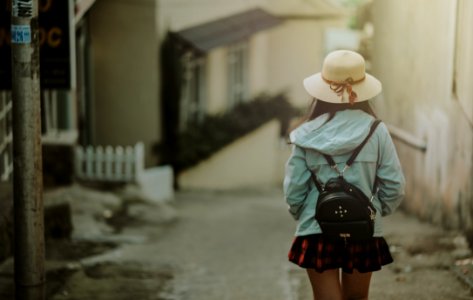 Girl In Blue Jacket And Black Leather Knapsack Walking On Street photo