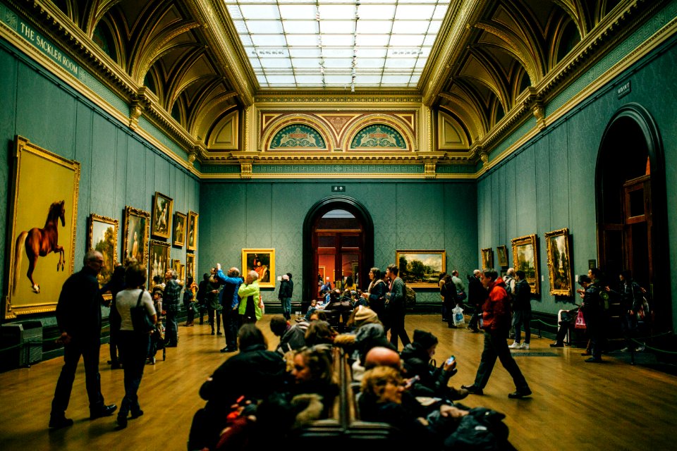 People Walking On Wooden Floor Inside Green Walled Building