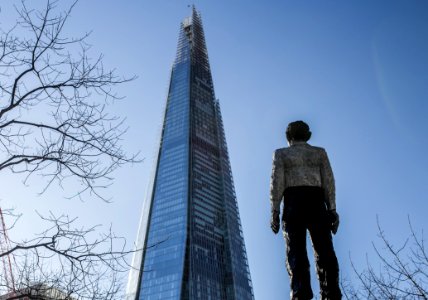 Man Standing In Front Of A Sunrise Building Under Blue Sky