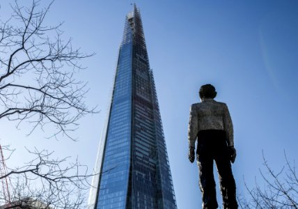 Man Standing In Front Of A Sunrise Building Under Blue Sky photo