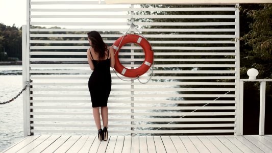 Woman In Black Sheath Dress Beside Swim Ring On Dock