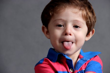 Child Wearing Blue And Red Stripes Polo Shirt Sticking Out Tongue photo