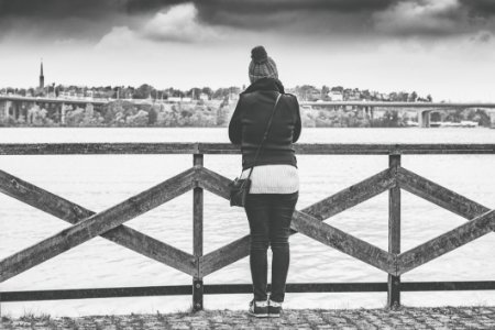 Woman Near Wooden Railing And Body Of Water Grayscale Photo photo