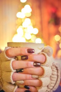 Person Holding A Mug Infront Of A Lighted Christmas Tree