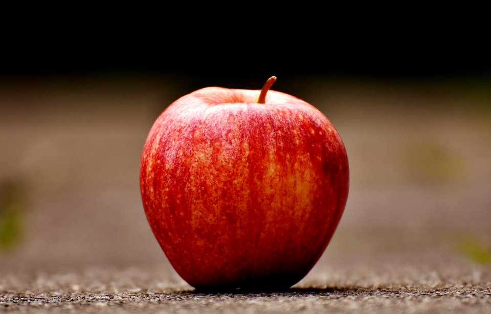 Shallow Focus Photography Of Red Apple On Gray Pavement