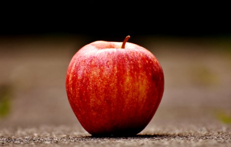 Shallow Focus Photography Of Red Apple On Gray Pavement photo